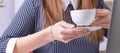 Coffee cup in businesswoman`s hand. Young woman working with documents and laptop close-up. Royalty Free Stock Photo