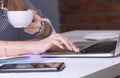 Coffee cup in businesswoman`s hand. Young woman working with documents and laptop close-up. Royalty Free Stock Photo