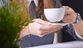 Coffee cup in businesswoman`s hand. Young woman working with documents and laptop close-up. Royalty Free Stock Photo