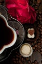 coffee cup with chocolate pralines and a red rose on a wood romantic table ready for lovers. Royalty Free Stock Photo