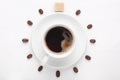 Coffee cup and coffee beans with cane sugar cube against white background forming clock dial viewed from top