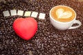 Coffee cup and coffee beans, red heart on table Royalty Free Stock Photo