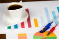 Coffee cup with colorful bar and pie charts and pens Royalty Free Stock Photo