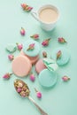 Coffee cup and colorful macaron on pastel background top view.