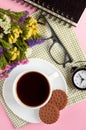 Coffee cup with cookies, alarm clock, flowers, mascara, on pink background composition Royalty Free Stock Photo