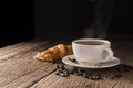 Coffee cup with croissant, bread, bakery or breakfast cake laying on a wooden table on a black needle background Royalty Free Stock Photo