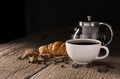 Coffee cup with croissant, bread, bakery or breakfast cake laying on a wooden table on a black needle background Royalty Free Stock Photo