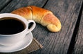 Coffee cup with a croissant breakfast