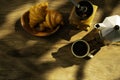 Coffee cup with a croissant and fresh coffee beans on an old wooden floor while camping in the forest