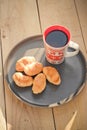 Coffee in a cup and croissants on a plate. Food and drinks. Plate on a wooden background