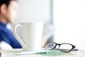 Coffee cup, eye glasses & pen over a book with blur background of a man Royalty Free Stock Photo