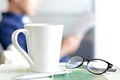 Coffee cup, eye glasses & pen over a book with blur background of a man Royalty Free Stock Photo