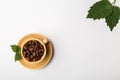 Coffee cup filled with coffee beans and green fresh leaves Royalty Free Stock Photo