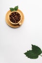 Coffee cup filled with coffee beans and green fresh leaves Royalty Free Stock Photo