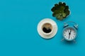 Coffee cup, flower pot and clock on blue background. Top view. Flat lay. Good morning concept Royalty Free Stock Photo