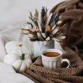 Coffee cup with flowers and pumpkins on a cozy plaid. Autumn still life. Breakfast in bed. Good morning. Stylish autumn flat lay.