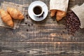 Coffee cup, freshly baked croissants, coffee beans on wood background Royalty Free Stock Photo