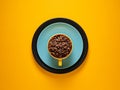 Coffee cup full of coffee beans over yellow background Royalty Free Stock Photo