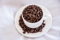 Coffee cup full of coffee beans on sleeping pillow with quilt in white color Royalty Free Stock Photo