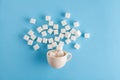 Coffee cup full of sugar cubes isolated on pastel blue background, hidden sugar in sweet drinks, diabetes risk