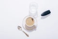 Coffee cup, glass of water, spoon and black milk frother on white table. Top view, flat lay Royalty Free Stock Photo