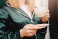 Coffee cup in hand beautiful young woman in pajamas