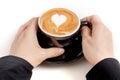 Coffee cup with heart shape latte art on top, hand holding the c Royalty Free Stock Photo