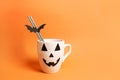 Coffee cup with jack o lantern face on orange background. Halloween concept Royalty Free Stock Photo