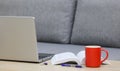 Coffee cup, laptop and a book on a table near the sofa