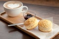 Coffee cup of latte art served with scones and homemade blueberry jam on wooden background (Selective focus)