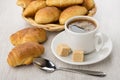 Coffee cup, lumpy sugar, croissants in wicker basket and spoon