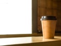 Coffee cup made of paper placed near the window.