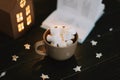 Coffee cup with marshmallows and a book on the table. Still life on dark background. Royalty Free Stock Photo