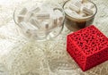 Coffee cup with marshmallows glass bowl with marshmallows red ring box on beige lace tablecloth vintage romance surprise