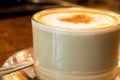 Coffee cup with milk froth on wooden table.