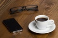 Coffee cup, mobile phone an glasses on a wooden