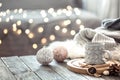 Coffee cup over Christmas lights bokeh in home on wooden table with sweater on a background and decorations. Holiday decoration,