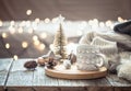 Coffee cup over Christmas lights bokeh in home on wooden table with sweater on a background and decorations. Holiday decoration Royalty Free Stock Photo