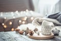 Coffee cup over Christmas lights bokeh in home on wooden table with sweater on a background and decorations. Holiday decoration, Royalty Free Stock Photo