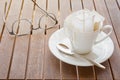 Coffee cup with packaged coffee on wooded table, blurred eyeglasses in background