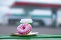 Coffee cup with a pink donut on a background of a gas station. Breakfast is on the way. Royalty Free Stock Photo