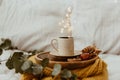 Coffee cup placed on a wooden tray and warm sweater with background bokeh blur of lights. Morning in Bed. Royalty Free Stock Photo