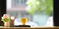 A coffee cup is putting on a wooden counter bar surrounded by a notebook, book, and potted. Royalty Free Stock Photo