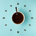 Coffee cup and roasted beans arranged as clock face on blue background, top view. Coffee time symbol. Interesting idea energy and Royalty Free Stock Photo