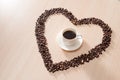 Coffee cup with roasted beans shapes love around on wood background Royalty Free Stock Photo