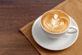 Coffee cup of rosetta latte art place on napkin on wooden background