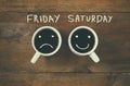 Coffee cup with sad and happy faces next to friday saturday phrase background. vintage filtered. happy weekend concept