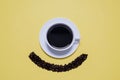 Coffee cup and saucer with beans making a minion smiley face on yellow Royalty Free Stock Photo