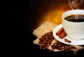 Coffee cup with saucer and coffee beans on burlap over dark Royalty Free Stock Photo