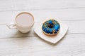 Coffee in a cup with a saucer with a donut in blue-yellow color.